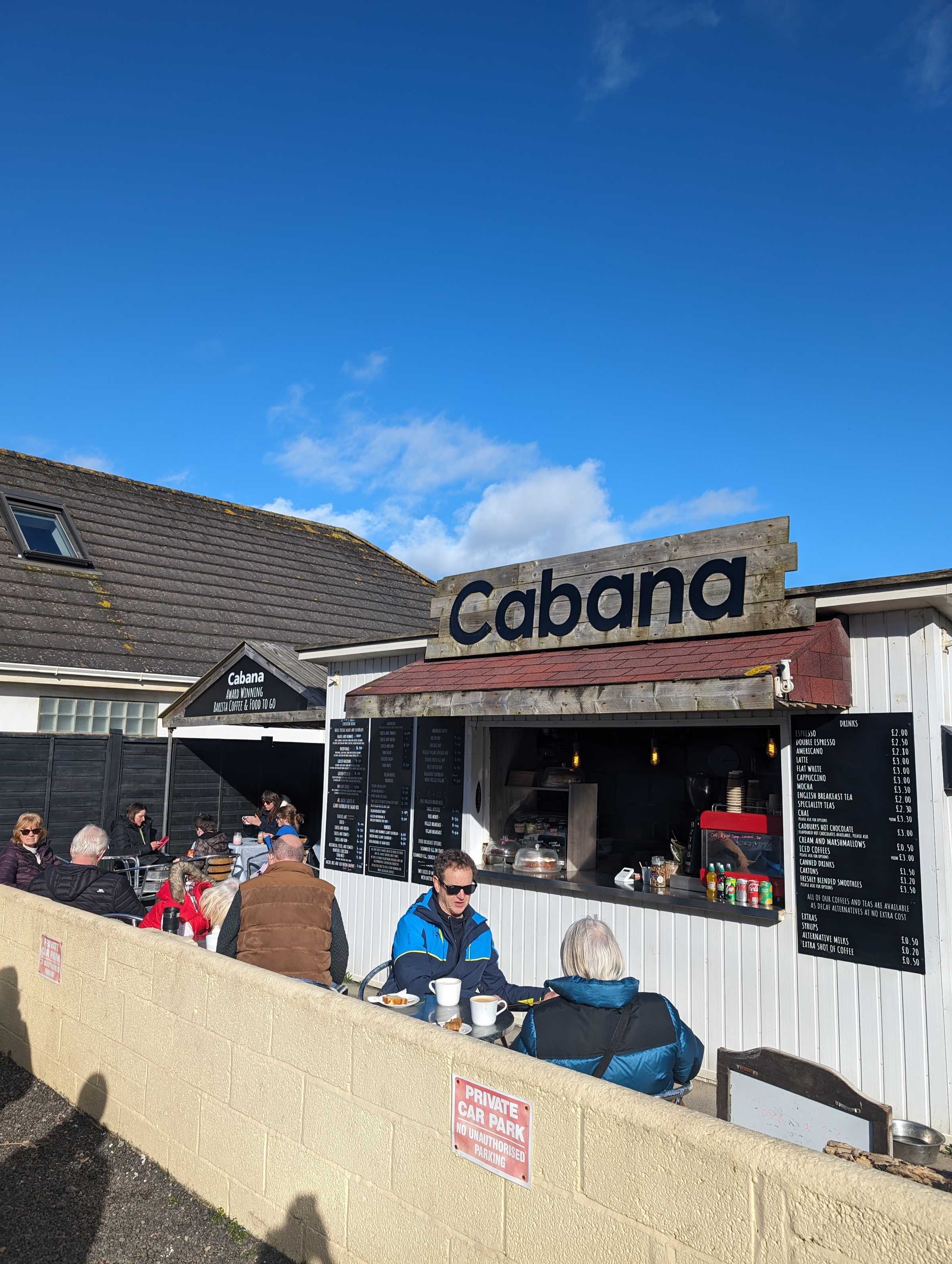 Customers at outdoor tables in front of the Cabana kiosk on a sunny day